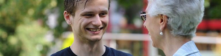 Caritas-Mitarbeiter im Gespräch mit einer alten Dame