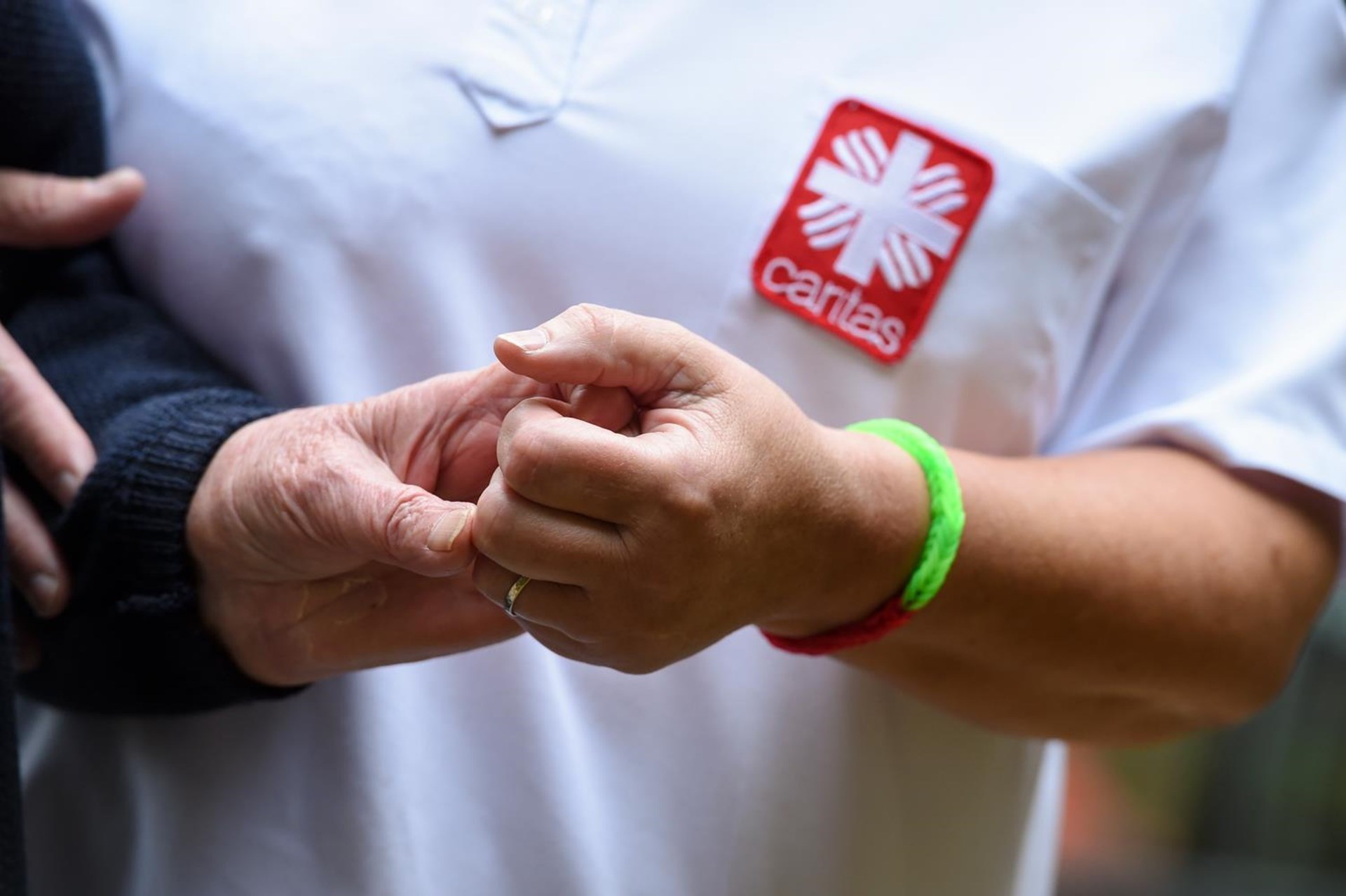 Eine Pflegerin hält die Hand einer Seniorin.